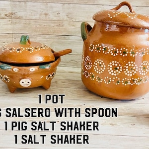May include: A collection of terracotta kitchenware, including a large pot with a lid, a pig-shaped salsero with a spoon, a pig-shaped salt shaker, and a small salt shaker. The items are decorated with white and green dot patterns.