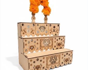 May include: A three-tiered wooden display stand with laser-cut Day of the Dead-themed designs, including sugar skulls and floral patterns. The stand is topped with a garland of bright orange flowers, perfect for showcasing items.