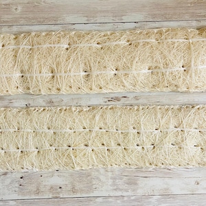 May include: Two rectangular, beige woven mats with a grid-like pattern. Each mat is made of natural fibers and has a series of small, evenly spaced holes. The mats are tied with white string at the ends.