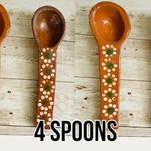 May include: Four terracotta-colored wooden spoons with a floral design in white and green. The spoons have a rounded bowl and a long handle. The text "4 SPOONS" and the letter "A" are visible in the image.