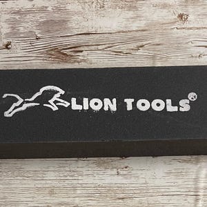 May include: A black rectangular box with the words "LION TOOLS" in white lettering and a white lion logo. The box is sitting on a wooden surface.