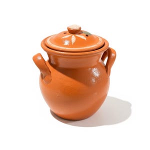 May include: A terracotta-colored ceramic pot with a matching lid. The pot has two handles and a round body. The lid features a floral design and small holes. The pot is likely used for cooking or storage.