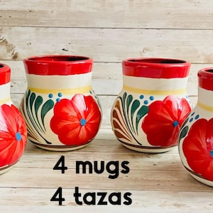 May include: Four ceramic mugs with a red rim and a floral design. The mugs have a white base with a red poppy flower, green leaves, and blue accents. The text "4 mugs" and "4 tazas" is visible.