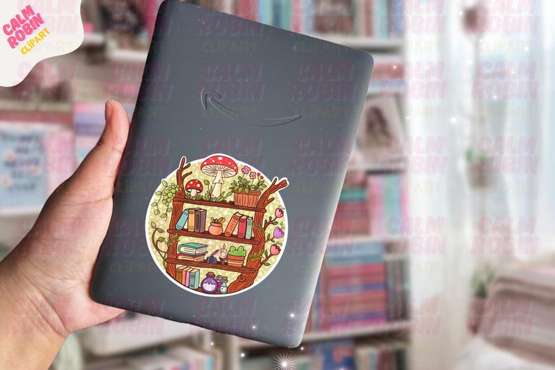 Puede incluir: Un lector de libros electr&oacute;nico negro con una pegatina colorida con un dise&ntilde;o de estanter&iacute;a. La pegatina incluye libros, plantas y setas. La pegatina es redonda y tiene un estilo caprichoso.