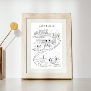 Peut inclure: Illustration en noir et blanc encadrée, représentant une route sinueuse avec diverses scènes, dont une maison, des personnes et un phare. Le texte "ANNA & JULIA" est en haut. Le cadre est en bois clair.