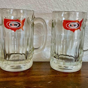 May include: A set of three ceramic mugs with a speckled, matte finish. The mugs are in shades of cream, light gray, and dark gray. Each mug has a simple, minimalist design and a rounded handle.