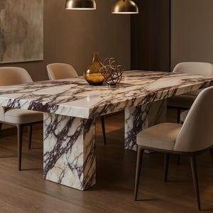 Puede incluir: Una mesa de comedor rectangular con tapa de mármol y base a juego. La mesa está rodeada de seis sillas tapizadas en beige con patas de madera oscura. Un jarrón y una escultura decorativos están sobre la mesa.