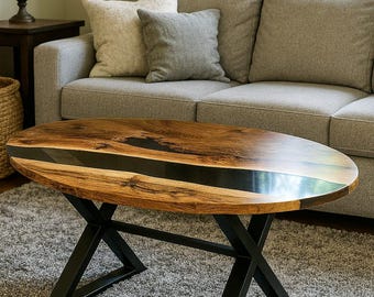 Mesa de centro ovalada de borde vivo: resina epoxi negra y patas de hierro en forma de X