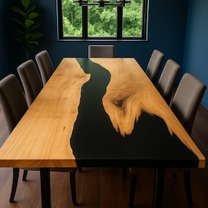May include: A large, rectangular dining table with a light wood surface and a black epoxy river down the center. The table is supported by a black metal base and surrounded by gray upholstered chairs. The table measures approximately 108 inches long.