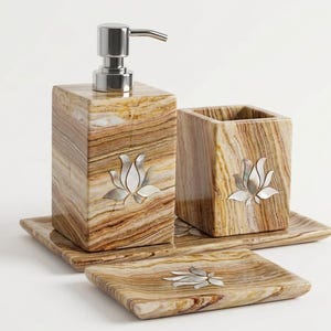 Può includere: Un set di accessori da bagno realizzato in pietra a strisce marroni e marrone chiaro, composto da un dispenser di sapone quadrato con pompa argentata, un portaspazzolino quadrato e un portasapone rettangolare. Ogni pezzo è intarsiato con un loto in madreperla.
