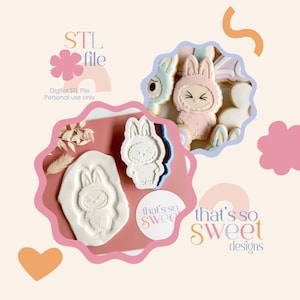 May include: An image featuring bunny-shaped cookie cutters and cookies. The image includes the text "STL file" and "that's so sweet designs". The cookies are decorated with pastel colors. The image also shows a bunny-shaped impression in dough.