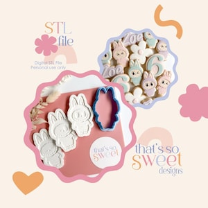 May include: An image featuring bunny-shaped cookies, a cookie cutter, and the text "STL file." The cookies are decorated with pastel colors and the number "6." The text "that's so sweet designs" is also visible.