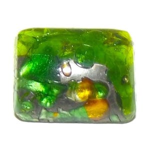 May include: A square, translucent glass bead with a vibrant, layered design. The bead features shades of green, yellow, and silver, creating a textured, abstract pattern. The edges are slightly rounded, and the overall effect is luminous.