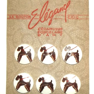 May include: Vintage ceramic buttons on a cardboard backing. Each button features a brown dog with a red leash on a white background. The card has the word "Elegance" in red script.