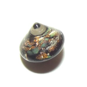 May include: A small, rounded glass bead with a dark base, featuring copper and teal accents. The bead has a clear, conical top and a speckled design, creating a unique, decorative element.