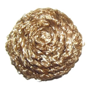 Può includere: Un oggetto decorativo rotondo, color oro, con un design a spirale. L'oggetto è realizzato in materiale lucido a forma di nastro, creando un aspetto strutturato. Lo sfondo è bianco.