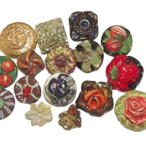 Può includere: Una collezione di bottoni decorativi in ceramica di varie forme e colori. I bottoni presentano disegni floreali, a spirale e geometrici, con colori come oro, rosso, verde e marrone. Alcuni bottoni hanno texture in rilievo e dettagli intricati.