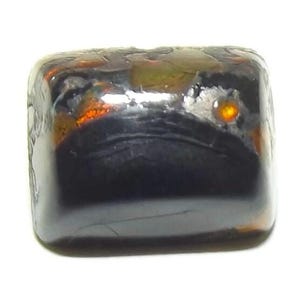 Puede incluir: Un objeto oscuro, rectangular y translúcido con un acabado brillante. El objeto tiene una mezcla de tonos marrón oscuro y naranja, con una pequeña mancha naranja brillante visible en una esquina. La forma general es un rectángulo redondeado.