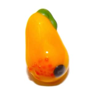 Puede incluir: Una pieza de arte de vidrio hecha a mano con forma de pimiento amarillo con un tallo verde. El pimiento tiene un acabado brillante con detalles naranjas y rojos y una mancha negra.