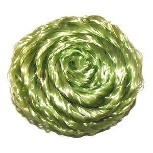 Può includere: Una palla strettamente avvolta di nastro verde chiaro e lucido. Il nastro sembra essere fatto di un materiale sintetico, con una leggera lucentezza che riflette la luce. La forma generale è circolare, simile a una bobina ben compatta.