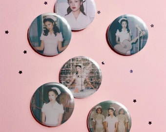 May include: Five circular pin-back buttons featuring photographic portraits of a person wearing a white nurse uniform and cap. The images show the person in various poses, including playing a guitar and standing in a laboratory setting.