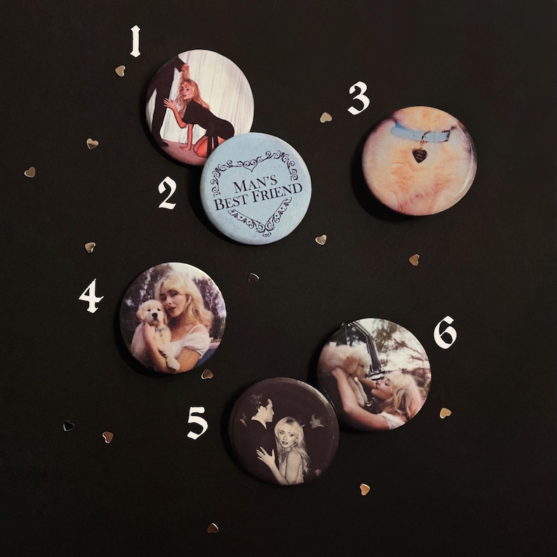 May include: A collection of six circular pin-back buttons featuring various photographic prints. One button is light blue with the text "MAN'S BEST FRIEND" inside a decorative heart frame. Other buttons display images of a person with a dog.