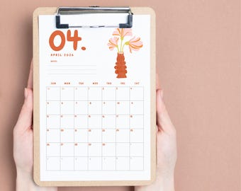 May include: A clipboard displays an April 2026 calendar page. The calendar has a minimalist design with orange text and a floral illustration. The calendar is held by two hands against a solid pink background.