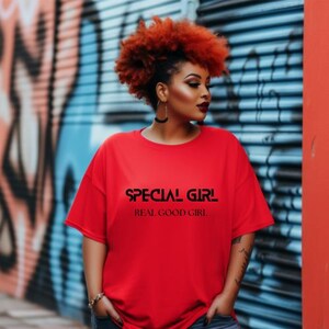 Może przedstawiać: Czerwona koszulka z napisem "SPECIAL GIRL" nad "REAL GOOD GIRL" w kolorze czarnym. Osoba nosząca koszulkę ma rude włosy. Tło to ściana pokryta graffiti.