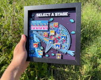 May include: Framed artwork with a video game theme, displaying the text "SELECT A STAGE." The artwork showcases a vibrant level map with character icons and the words "FINAL RUSH." The frame is black.