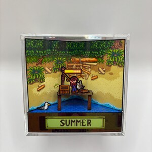 May include: A pixelated diorama featuring a fishing scene with a figure on a wooden dock. The scene includes a seagull, sand, water, and lush greenery. The word "SUMMER" is displayed on a green banner at the bottom.