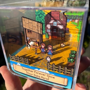 May include: A miniature diorama in a clear acrylic box depicts a pixelated farm scene. Two figures stand near a house and barn, with a fence and crops in the foreground. Text on the base reads "Together Forever Since [Your Date Here]."