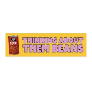 May include: A yellow bumper sticker with the text "THINKING ABOUT THEM BEANS" in pink letters. A can of "BEST YET BEANS" is on the left side of the sticker, with a red label and a picture of beans.