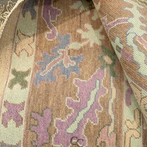 K&ouml;nnte beinhalten: Gerollter Teppich mit sich wiederholendem Blumenmuster in Braun-, Lila-, Blau- und Gr&uuml;nt&ouml;nen. Der Teppich hat ein weiches, strukturiertes Aussehen. Der Text "CARPETS CITY" ist sichtbar.
