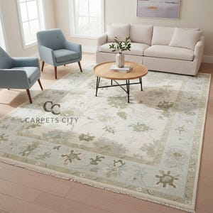 May include: A large, rectangular area rug with a floral pattern in shades of green and beige. The rug has a border with a lighter green hue and fringe along the edges. The text "CARPETS CITY" is visible on the rug.