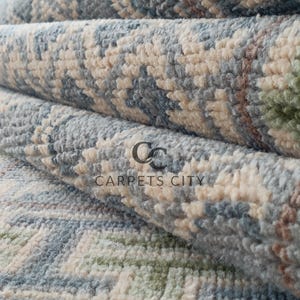 Handmade wool runner rug featuring a geometric lattice design in soft beige, blue, and green tones with tribal border details. This long hallway rug adds timeless style to entryways, kitchens, or bedside décor. Durable handwoven construction with fringe edges enhances farmhouse, boho, and modern interiors. Neutral yet colorful design makes it versatile for layering or as a statement runner. Perfect handmade rug for hallways, narrow spaces, and unique home décor accents.