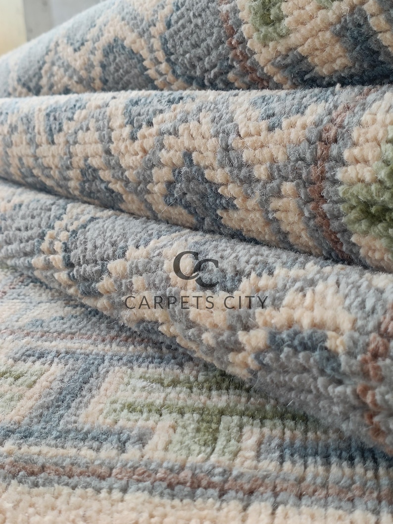 Handmade wool runner rug featuring a geometric lattice design in soft beige, blue, and green tones with tribal border details. This long hallway rug adds timeless style to entryways, kitchens, or bedside décor. Durable handwoven construction with fringe edges enhances farmhouse, boho, and modern interiors. Neutral yet colorful design makes it versatile for layering or as a statement runner. Perfect handmade rug for hallways, narrow spaces, and unique home décor accents.