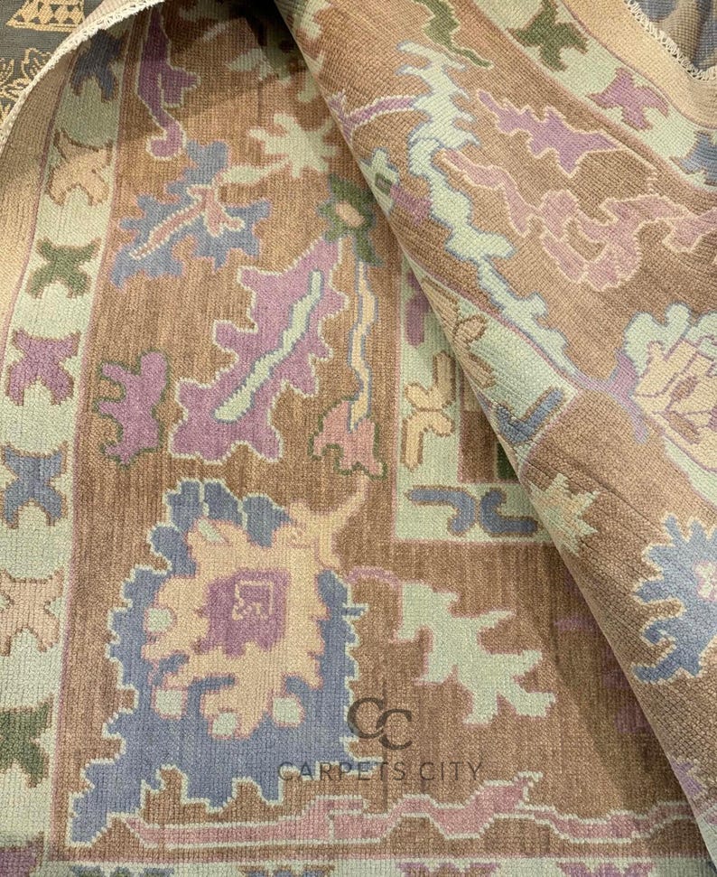 K&ouml;nnte beinhalten: Eine aufgerollte Teppichfl&auml;che mit einem detaillierten Blumenmuster in Braun-, Lila-, Blau- und Gr&uuml;nt&ouml;nen. Der Teppich tr&auml;gt unten den Text "CARPETS CITY". Das Design umfasst stilisierte Blumen- und geometrische Formen.