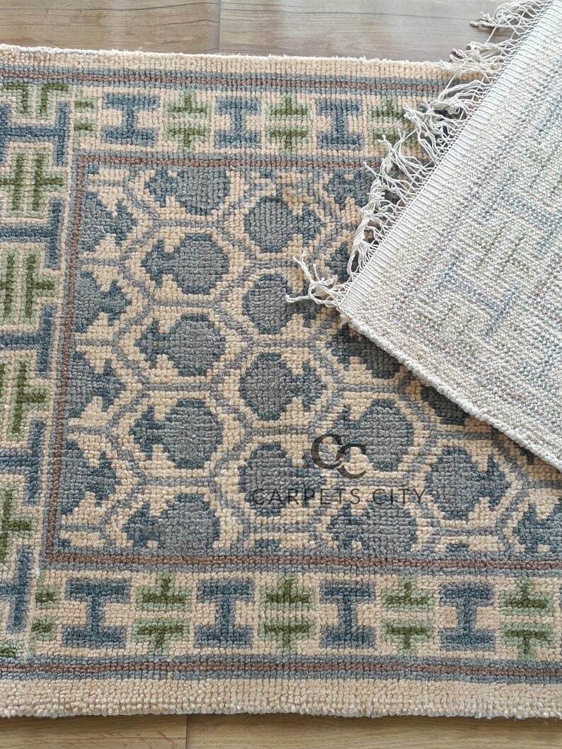 Handmade wool runner rug featuring a geometric lattice design in soft beige, blue, and green tones with tribal border details. This long hallway rug adds timeless style to entryways, kitchens, or bedside décor. Durable handwoven construction with fringe edges enhances farmhouse, boho, and modern interiors. Neutral yet colorful design makes it versatile for layering or as a statement runner. Perfect handmade rug for hallways, narrow spaces, and unique home décor accents.
