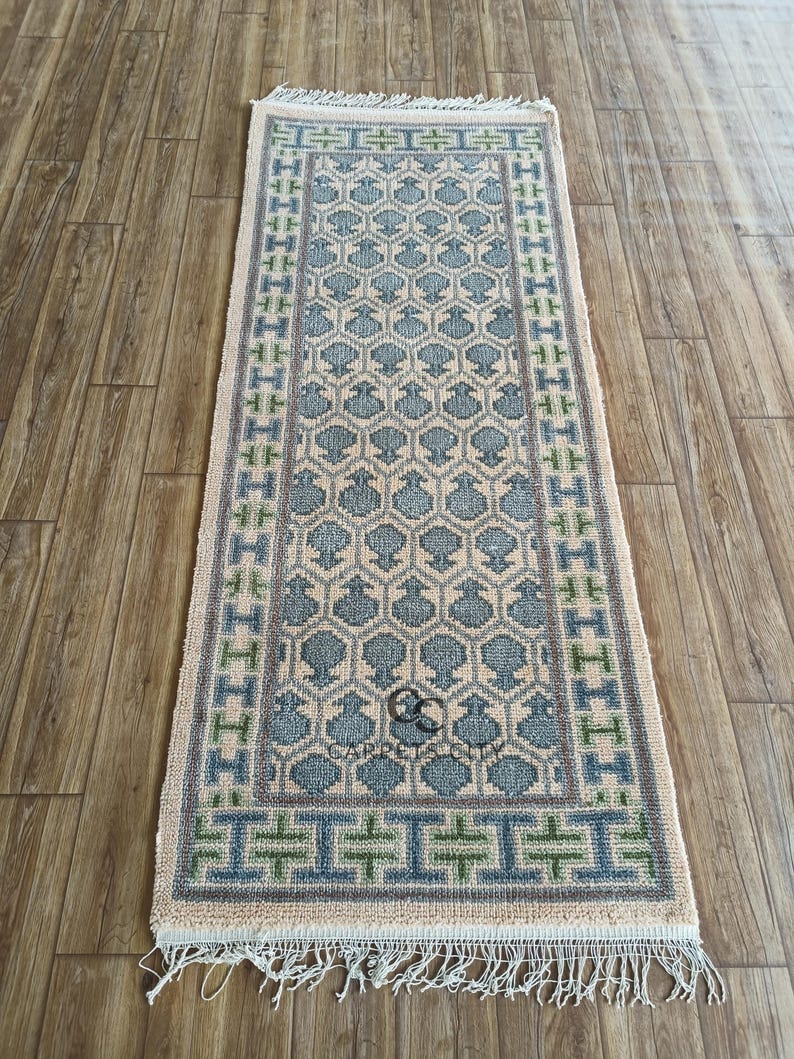 Handmade wool runner rug featuring a geometric lattice design in soft beige, blue, and green tones with tribal border details. This long hallway rug adds timeless style to entryways, kitchens, or bedside décor. Durable handwoven construction with fringe edges enhances farmhouse, boho, and modern interiors. Neutral yet colorful design makes it versatile for layering or as a statement runner. Perfect handmade rug for hallways, narrow spaces, and unique home décor accents.