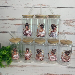 May include: Clear glass tumblers with bamboo lids and straws. Each tumbler features a woman illustration with inspirational quotes like "Believe yourself" and "Love yourself". The tumblers are decorated with butterflies.