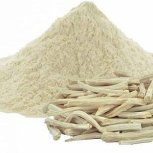 K&ouml;nnte beinhalten: Ein Haufen hellbeige Pulver neben einer Ansammlung von hellbraunen, getrockneten, st&auml;bchenartigen St&uuml;cken. Das Pulver ist fein gemahlen, und die St&auml;bchen haben eine raue Textur. Auf wei&szlig;em Hintergrund.