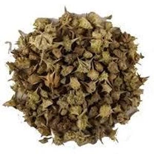 May include: A pile of dried, tan-colored Tribulus Terrestris plant parts, featuring spiky seed pods and small leaves. The image is a close-up shot against a white background, highlighting the texture and details of the plant material.