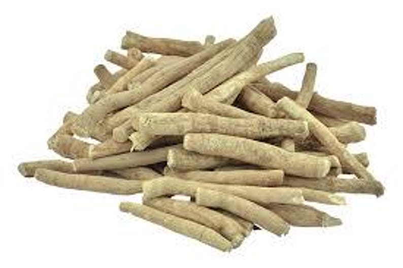 May include: A pile of ashwagandha roots, showcasing a light tan color and a rough, textured surface. The roots vary in size and shape, with some appearing thicker and others more slender. The background is plain white, highlighting the natural appearance of the roots.