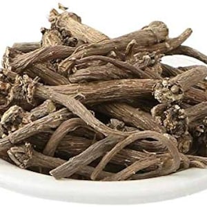 May include: A white ceramic bowl filled with dried, brown, root-like pieces. The pieces have a rough texture and varying lengths, with some curved and others straight. The image is well-lit, highlighting the natural colors and textures of the contents.