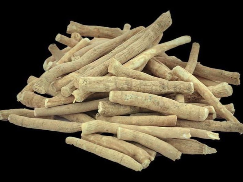 May include: A pile of ashwagandha root pieces, light tan in color, against a black background. The roots are cylindrical and have a rough, textured appearance. The image highlights the natural form of the herbal product.