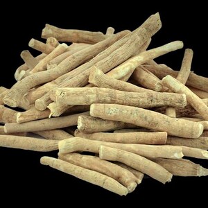 Peut inclure: Un tas de racines d'ashwagandha brun clair sur fond noir. Les racines, de tailles et formes vari&eacute;es, pr&eacute;sentent une surface rugueuse et textur&eacute;e. Certaines racines ont une couleur plus claire, presque blanche.