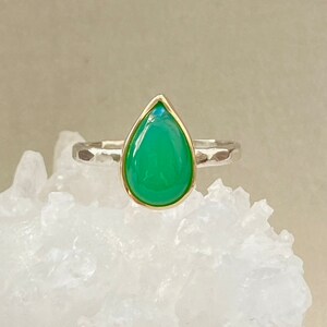 May include: A teardrop-shaped green gemstone ring with a gold setting and a hammered silver band.