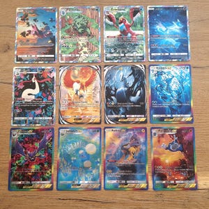May include: A collection of twelve rectangular trading cards featuring colorful illustrations of various creatures. Each card displays specific text, numerical values, and symbols, with some cards showcasing holographic or foil-like reflective finishes.