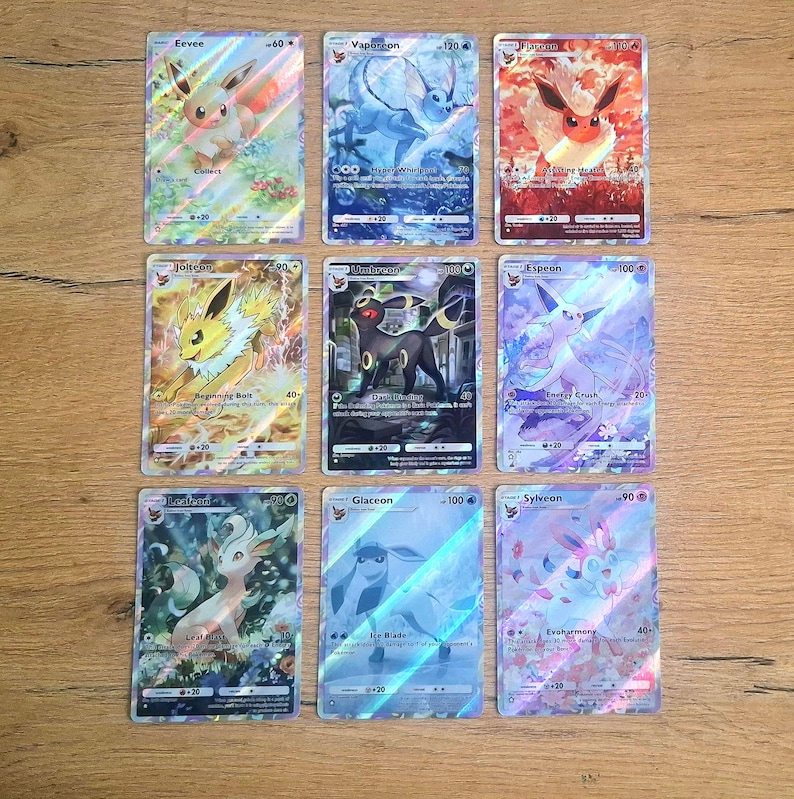 May include: A collection of nine holographic trading cards featuring Eevee and its evolutions, including Vaporeon, Flareon, Jolteon, Umbreon, Espeon, Leafeon, Glaceon, and Sylveon. Each card displays colorful character illustrations, text, and game stats.