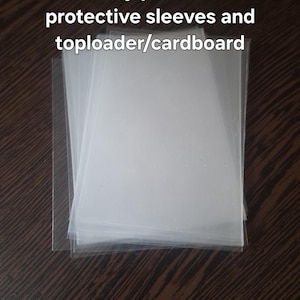 May include: A stack of clear, rectangular plastic protective sleeves for trading cards. The text "i safely pack with protective sleeves and toploader/cardboard" is overlaid on the image. These transparent sleeves are designed to hold and protect cards.